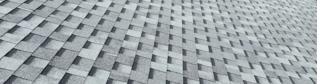 Storm-damaged asphalt shingle roof on a residential home in Pensacola, Florida