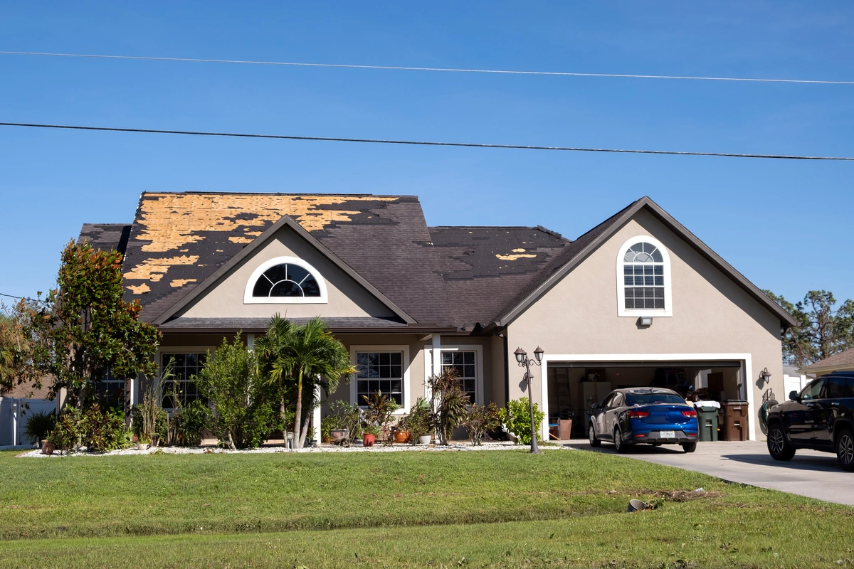 Family house with dark shingles that are ripped off by storm damage